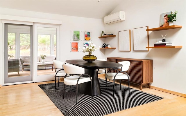 dining space featuring a wall unit AC, wood finished floors, lofted ceiling, and baseboards