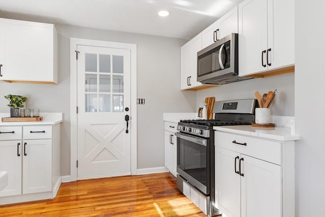 kitchen with white cabinetry, stainless steel appliances, and light hardwood / wood-style floors