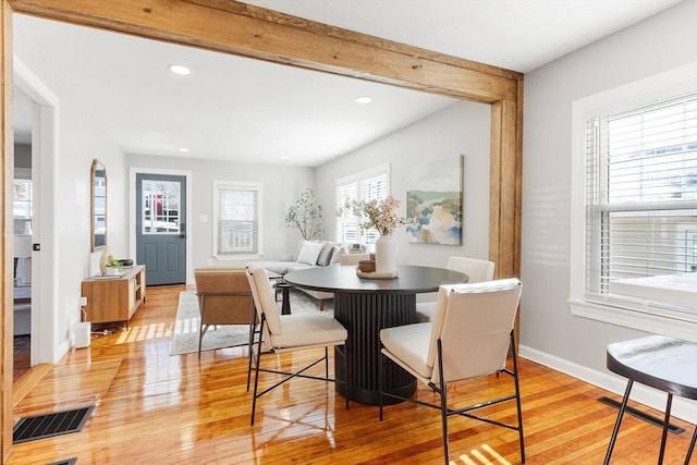 dining space with beamed ceiling and light hardwood / wood-style floors