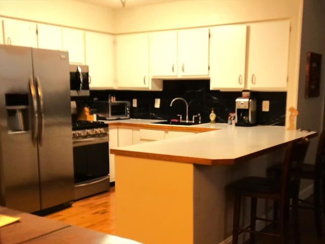 kitchen featuring stainless steel appliances, a breakfast bar, sink, and white cabinets