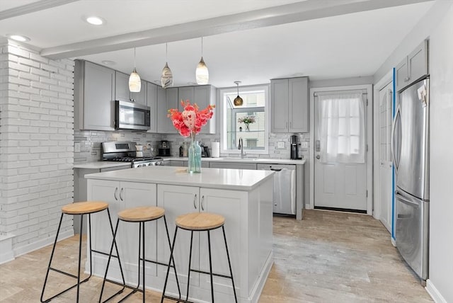 kitchen with decorative backsplash, a breakfast bar area, gray cabinetry, and stainless steel appliances