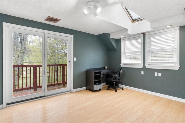 office with visible vents, a textured ceiling, plenty of natural light, and a skylight