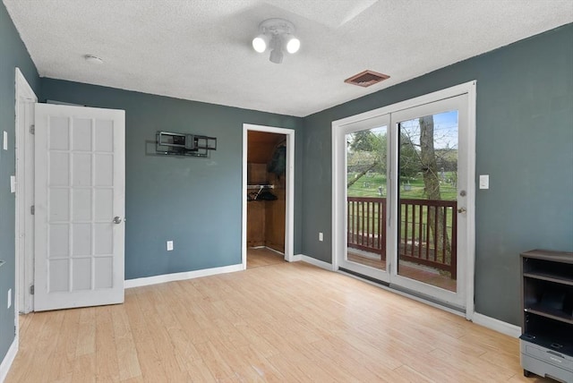 interior space featuring access to outside, a textured ceiling, visible vents, and wood finished floors