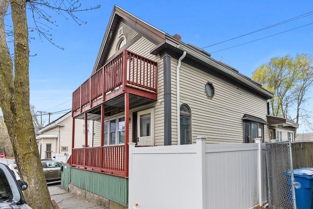 view of home's exterior with fence, a chimney, and a deck