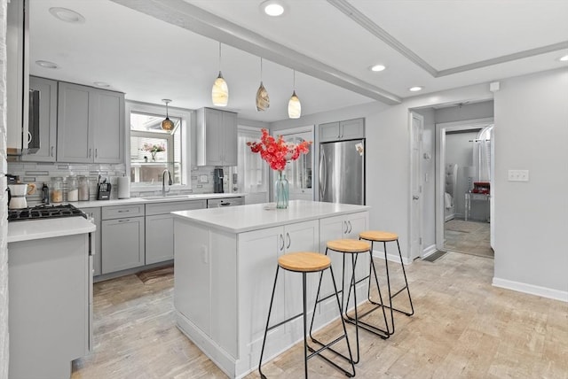 kitchen with freestanding refrigerator, a breakfast bar, recessed lighting, gray cabinets, and a sink