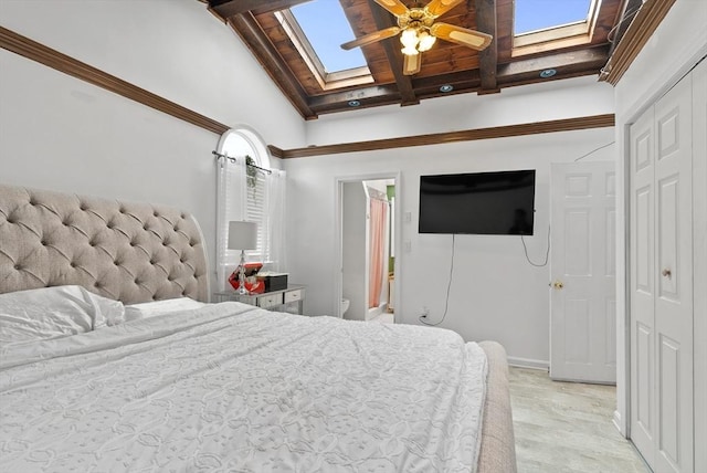 bedroom with beam ceiling, baseboards, light wood-type flooring, a skylight, and a closet