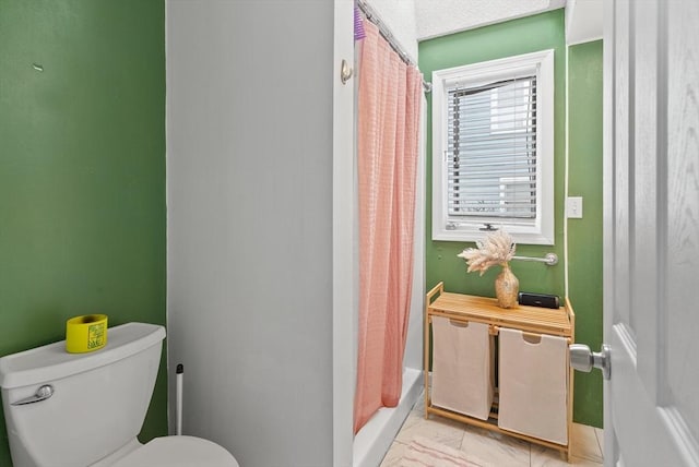 full bath with baseboards, marble finish floor, shower / bath combo, and toilet