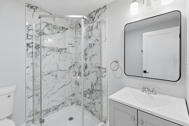 bathroom with toilet, a marble finish shower, and vanity