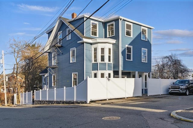view of front facade featuring fence and a chimney