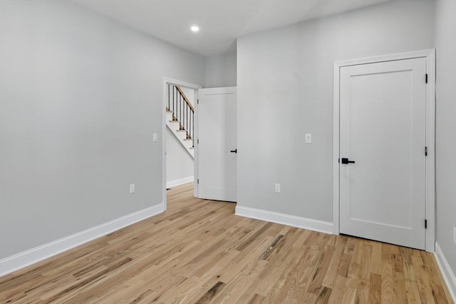 unfurnished room with stairway, baseboards, recessed lighting, and light wood-style flooring