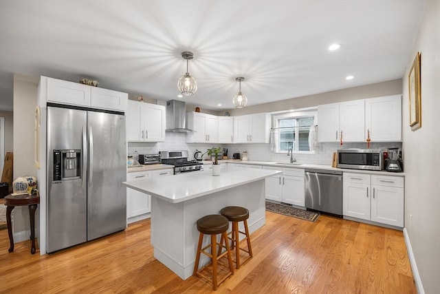 26 Weybosset St, Weymouth, MA 02191 - kitchen featuring stainless steel appliances, wall chimney exhaust hood, white cabinetry, backsplash, and light wood finished floors