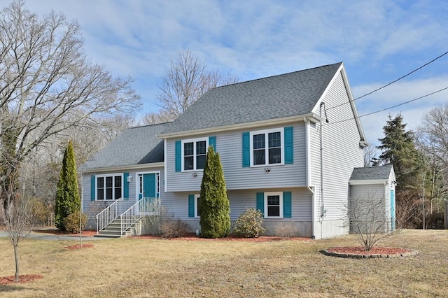 tri-level home with a front lawn and roof with shingles