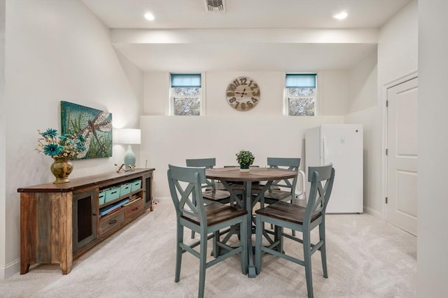 dining room featuring baseboards, a healthy amount of sunlight, visible vents, and light colored carpet