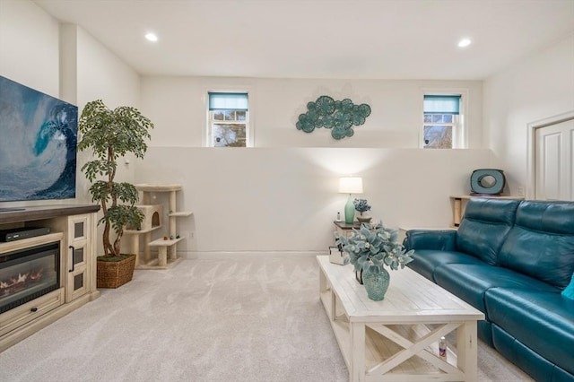 carpeted living room featuring a healthy amount of sunlight, recessed lighting, and a glass covered fireplace