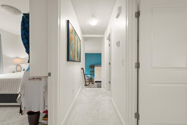 hallway featuring baseboards and light colored carpet