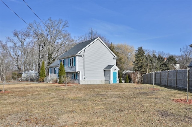 view of side of home featuring fence and a yard