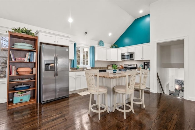 kitchen featuring appliances with stainless steel finishes, white cabinets, dark wood-style flooring, and a center island