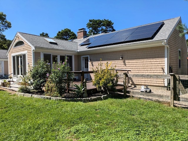 back of house with a yard, a wooden deck, and solar panels