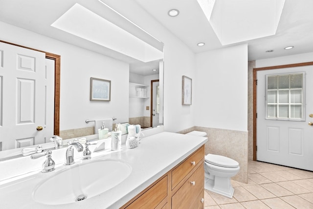 bathroom with vanity, toilet, tile walls, and tile patterned flooring