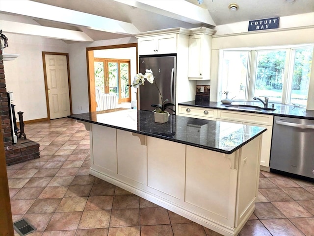 kitchen with a center island, appliances with stainless steel finishes, sink, dark stone counters, and light tile patterned flooring