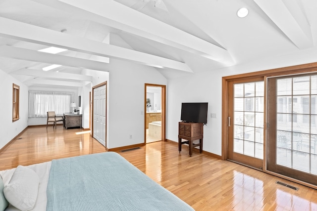 bedroom with multiple windows, light hardwood / wood-style floors, ensuite bathroom, and vaulted ceiling with beams