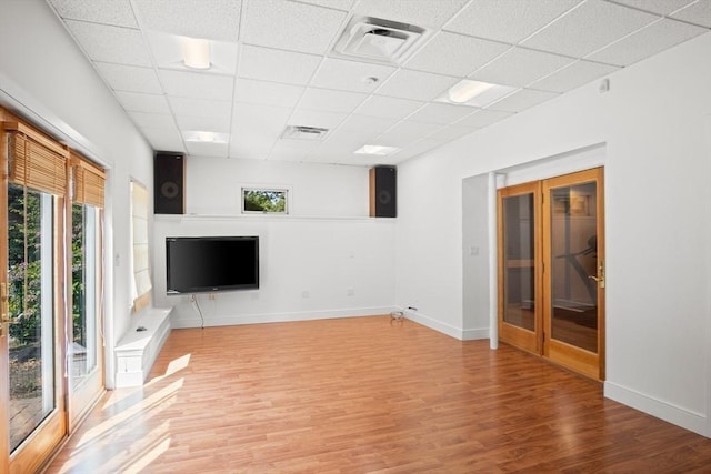 unfurnished living room with a drop ceiling and light hardwood / wood-style flooring