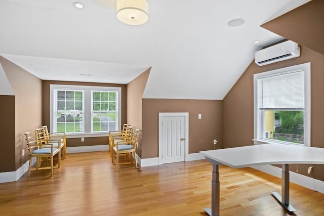 additional living space with light hardwood / wood-style floors, vaulted ceiling, and a wall unit AC