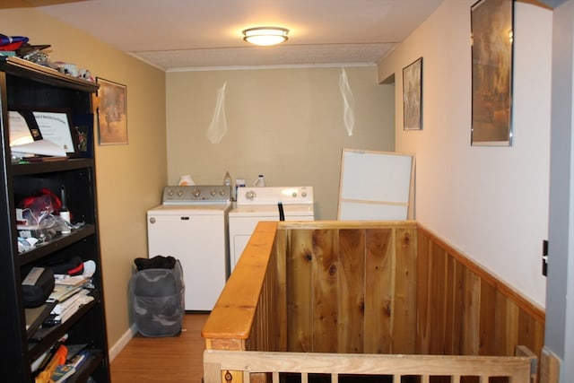 laundry area with washing machine and clothes dryer, wooden walls, and light hardwood / wood-style flooring