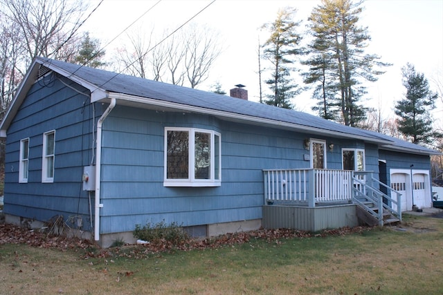 view of front of property featuring a garage, a front lawn, and a wooden deck