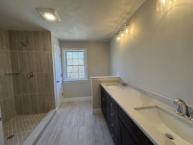 bathroom with a tile shower and vanity