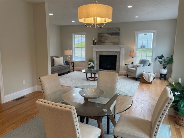 dining area with a fireplace, plenty of natural light, and light hardwood / wood-style flooring