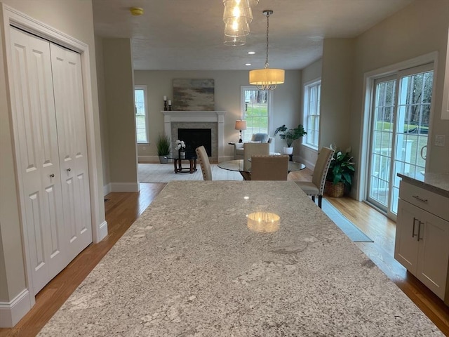 kitchen featuring a wealth of natural light, light stone counters, hanging light fixtures, and a brick fireplace