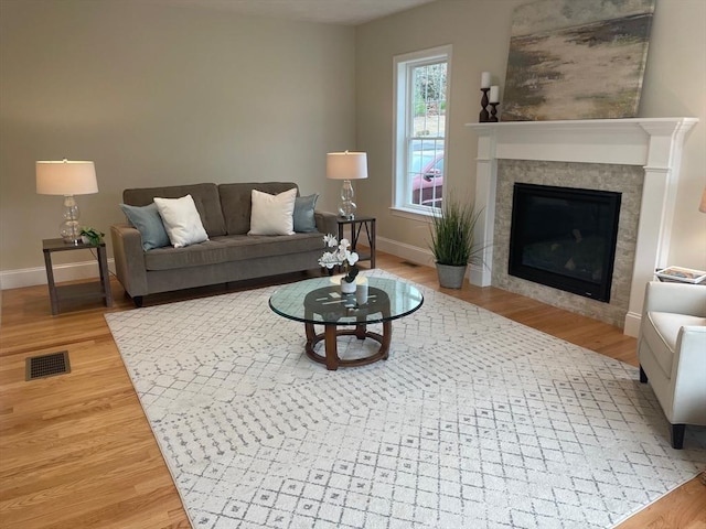 living room with a tile fireplace and hardwood / wood-style floors