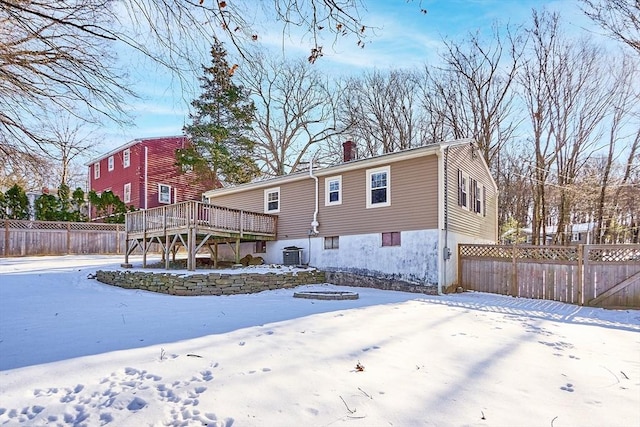 snow covered rear of property with a wooden deck and central air condition unit