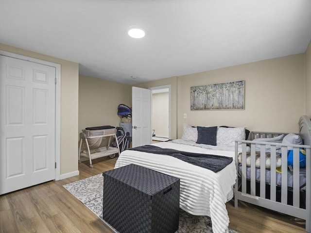 bedroom featuring wood finished floors, baseboard heating, and baseboards
