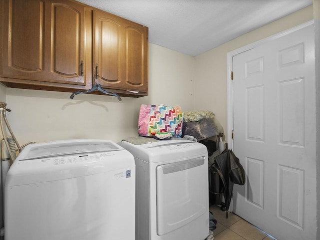 laundry area featuring cabinet space, separate washer and dryer, light tile patterned flooring, and a textured ceiling