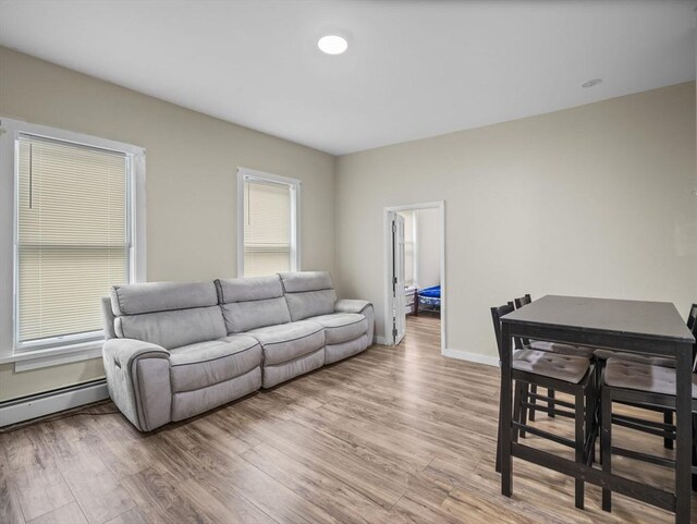 living area featuring light wood finished floors, baseboard heating, and baseboards