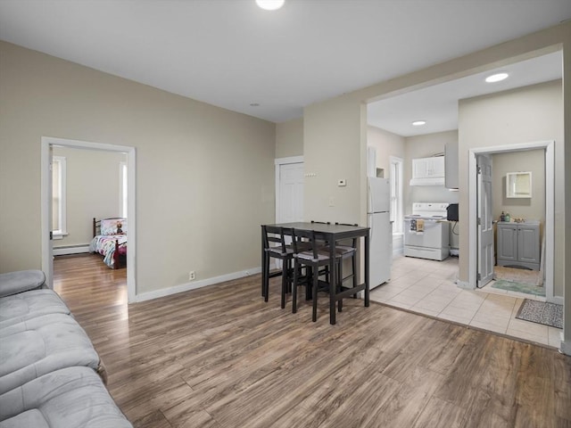 living area featuring light wood-type flooring, baseboard heating, baseboards, and recessed lighting