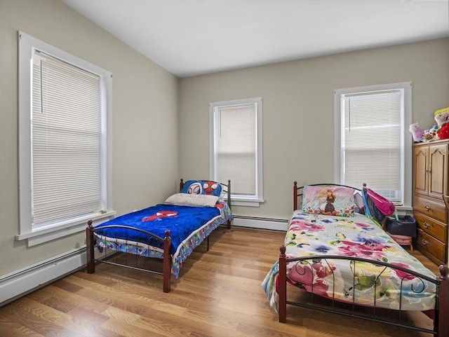 bedroom featuring wood finished floors, multiple windows, and baseboard heating