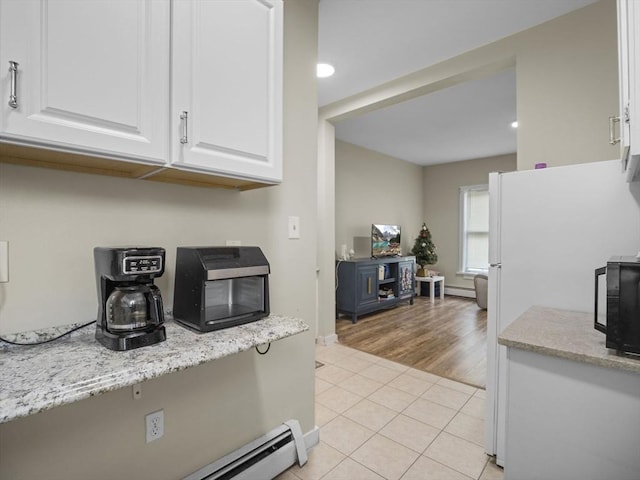 kitchen with white cabinetry, light tile patterned floors, freestanding refrigerator, a baseboard radiator, and baseboards