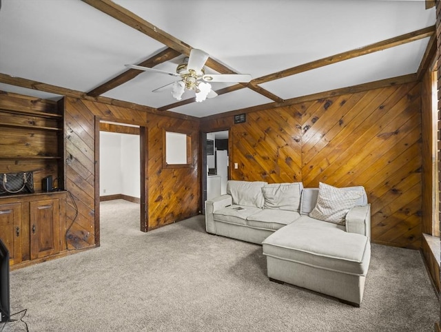 living area featuring beam ceiling, carpet, a ceiling fan, and wooden walls