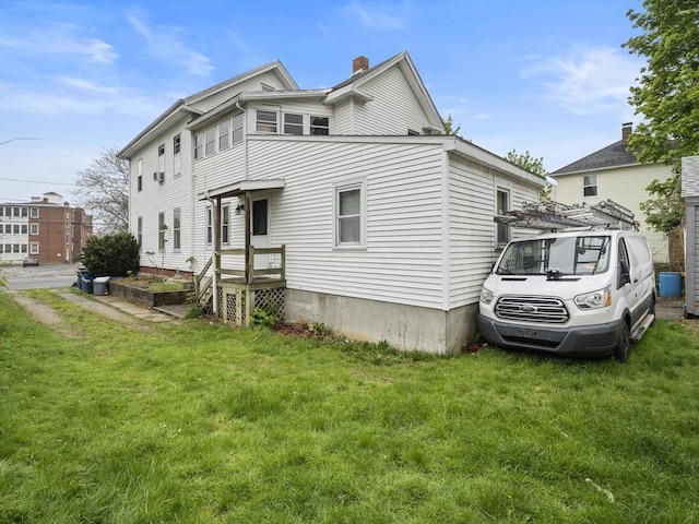 view of side of home with a chimney and a lawn