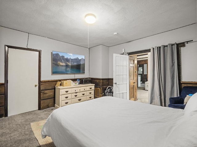 bedroom with light carpet, wainscoting, and a textured ceiling