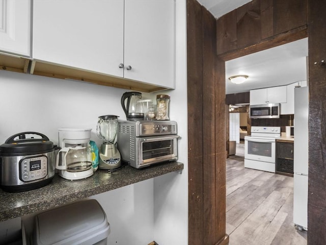 kitchen with white appliances, white cabinets, and light wood-style floors