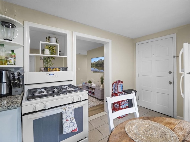 kitchen featuring white appliances, light tile patterned floors, and stone countertops