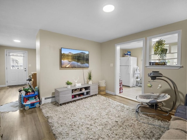 living room featuring wood finished floors, baseboards, and a baseboard heating unit