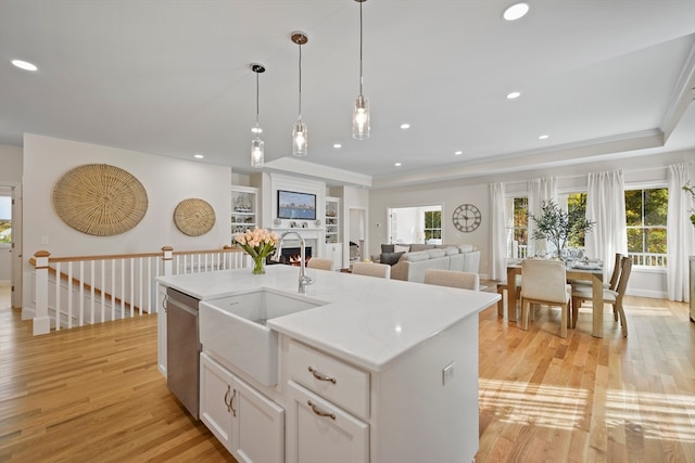 kitchen with a healthy amount of sunlight, sink, a kitchen island with sink, and light hardwood / wood-style flooring