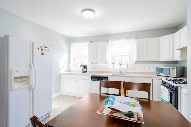 102 Gilman St, Somerville, MA 02145 - kitchen featuring white appliances, a sink, white cabinets, light tile patterned floors, and baseboards