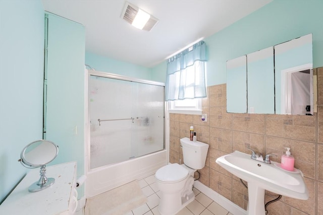 102 Gilman St, Somerville, MA 02145 - bathroom with toilet, tile patterned floors, bath / shower combo with glass door, tile walls, and a sink