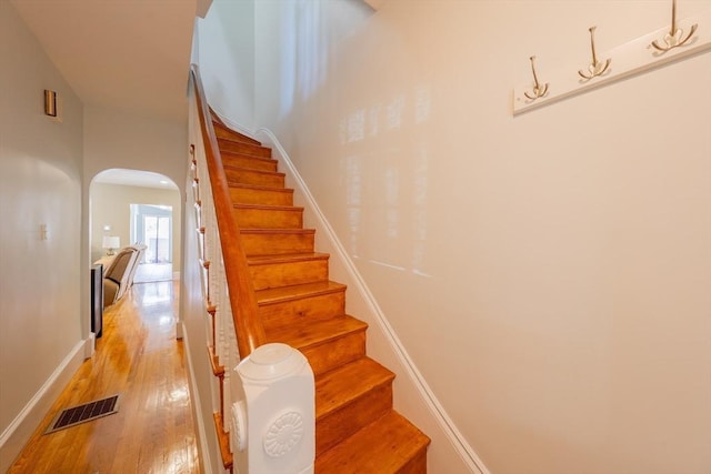 102 Gilman St, Somerville, MA 02145 - stairs featuring arched walkways, wood finished floors, and baseboards